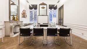 A conference room with a long table, black chairs, a whiteboard, and a fireplace. - Hotel Gravensteen (Ghent)