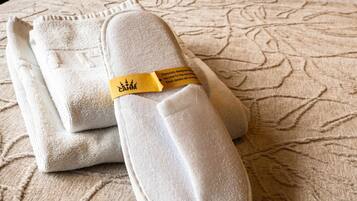 A pair of slippers with a yellow tag on a textured beige surface.