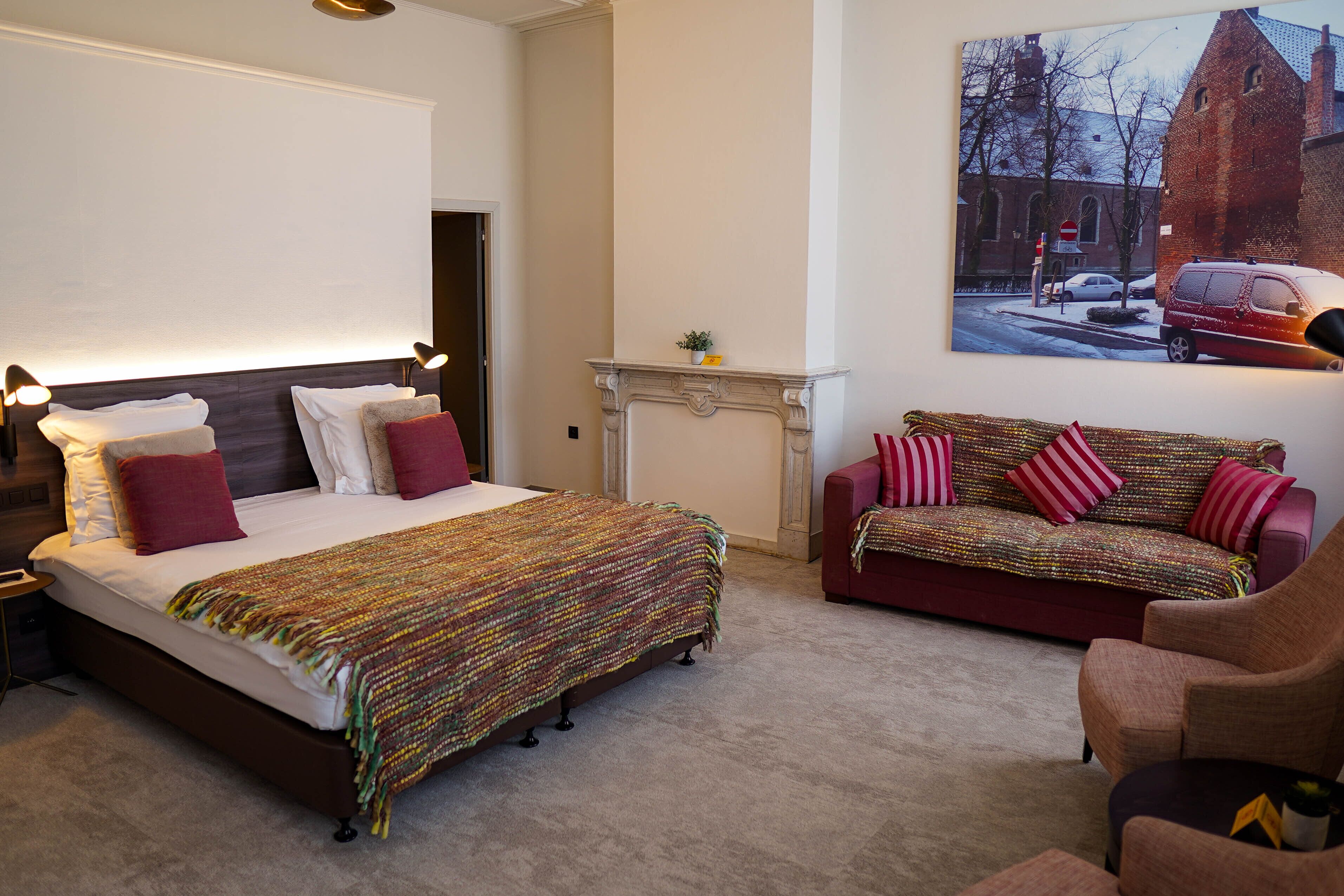 Un dormitorio con una cama grande, un sofá rojo y una chimenea.