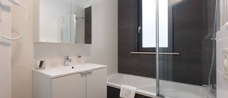 A modern bathroom with a white vanity, a glass-enclosed shower, and a large mirror.