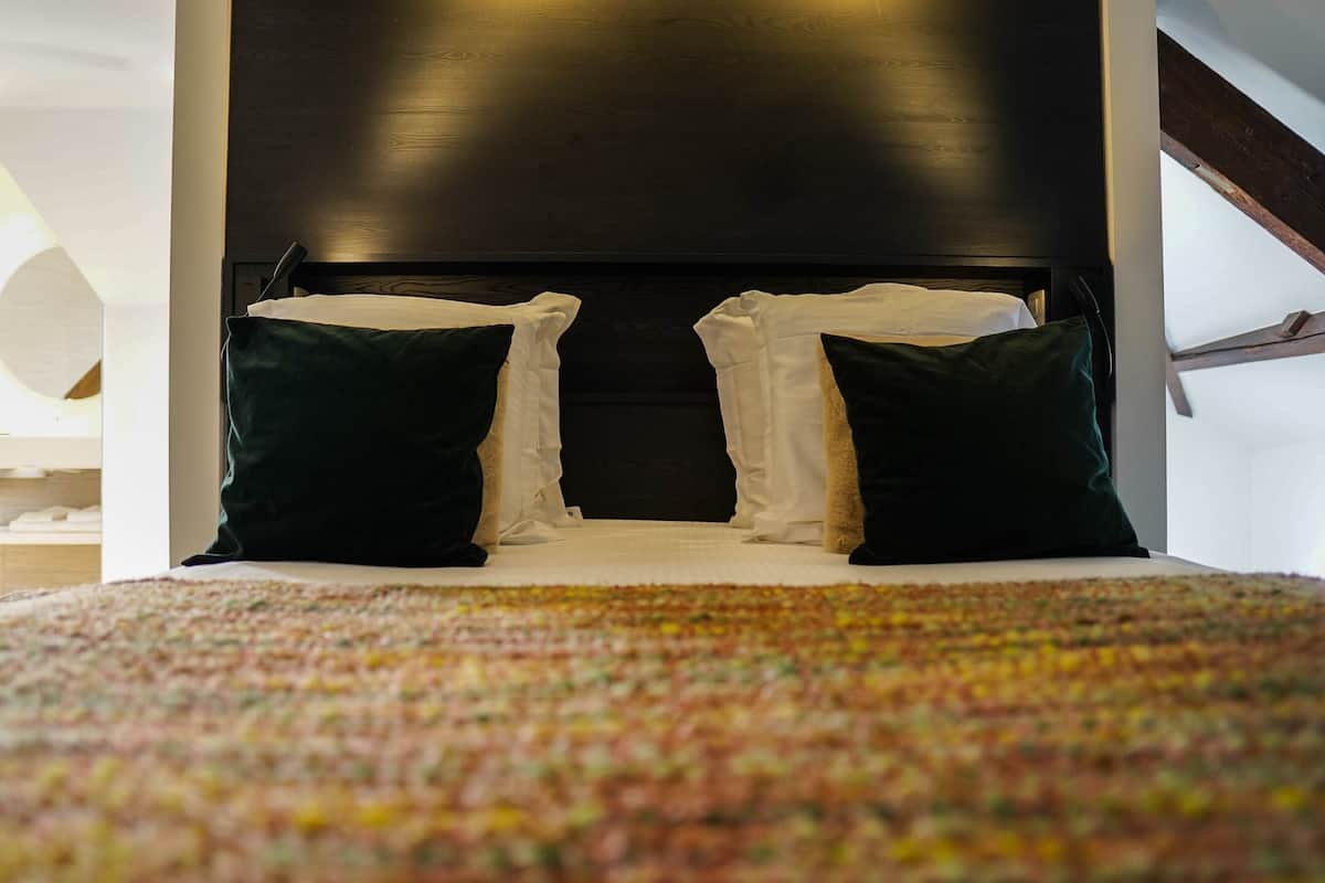 A bed with a colorful blanket, dark headboard, and two pillows.