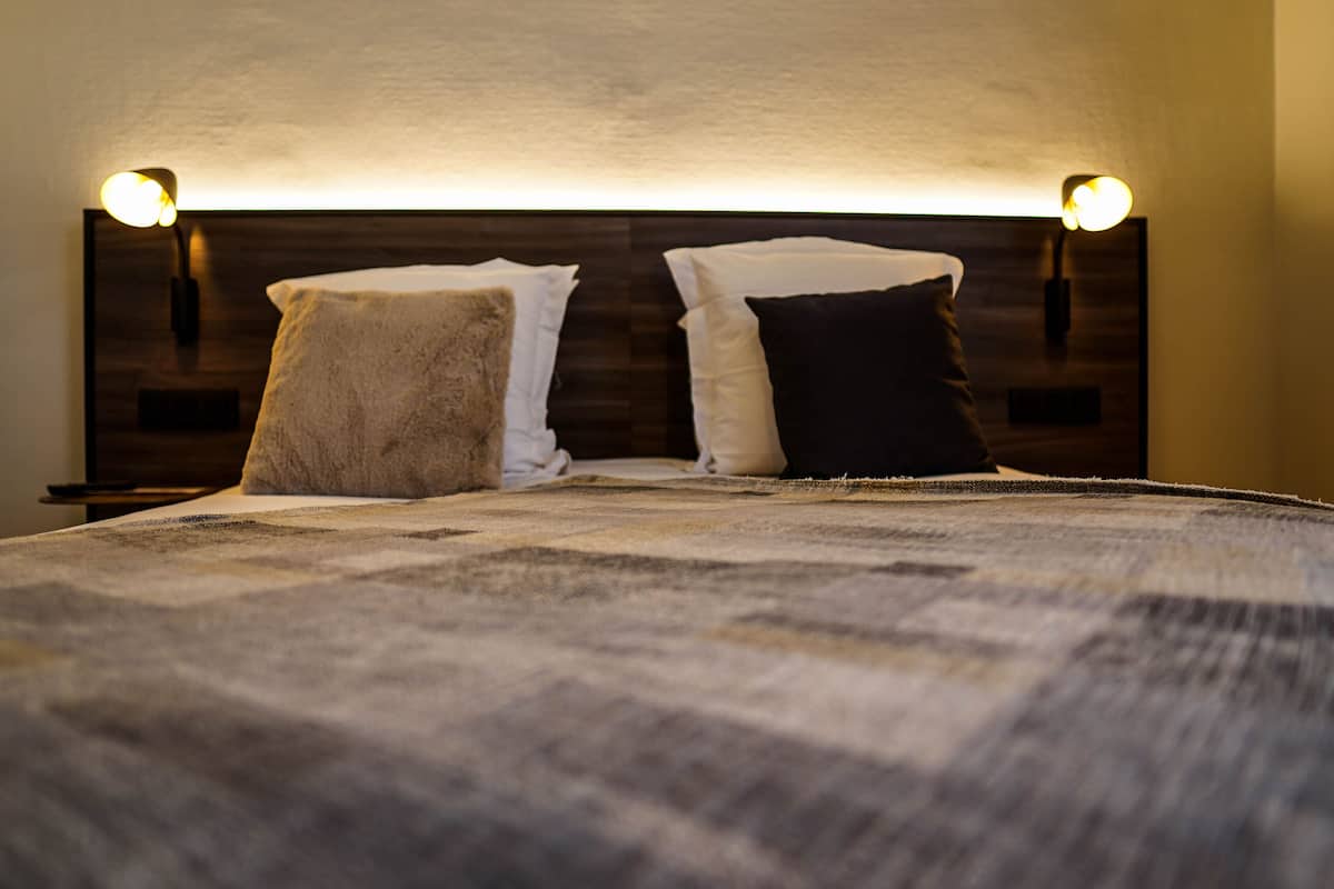 A bed with a headboard, two bedside lamps, and a blanket.