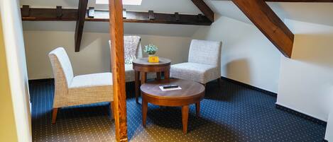 A cozy attic room with two wicker chairs, a small wooden table, and a skylight.