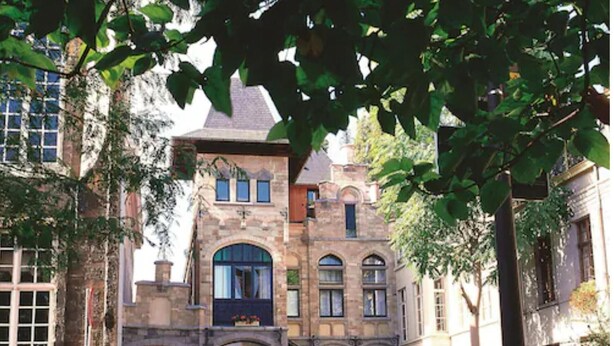 A historic building with a stone facade, multiple windows, and a central entrance with a stone archway. - Hotel Gravensteen (Ghent)