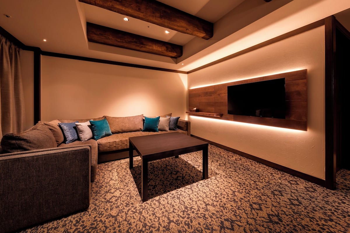A modern living room with a sectional sofa, a coffee table, and a flat-screen TV mounted on a wooden accent wall.