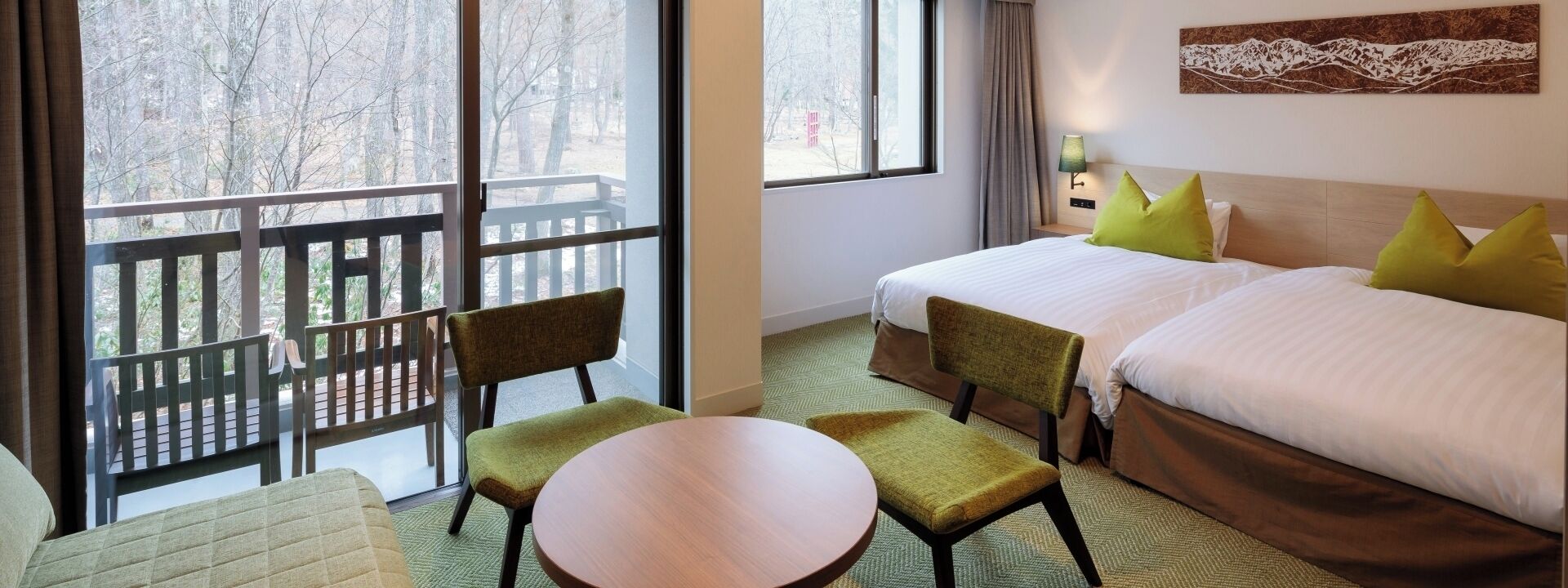 Habitación de hotel con dos camas, un balcón, una mesa redonda y una silla.