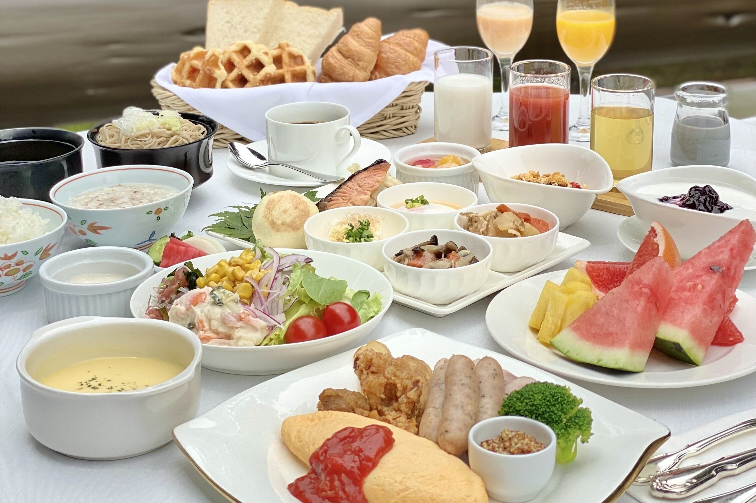 A table set with various breakfast items including waffles, croissants, and a selection of fruits and vegetables.