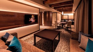 Una sala de estar acogedora con un televisor de pantalla plana montado en una pared de madera, una mesa de centro y una zona de estar con sofá y sillones.