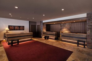 Un hall d'entrée moderne avec un tapis rouge, un comptoir d'accueil en bois et des murs en pierre.
