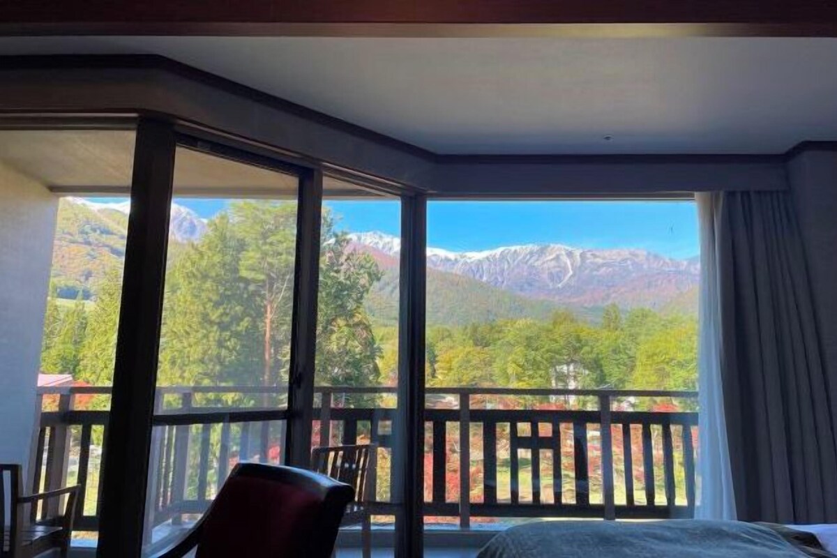 Una habitación de hotel con un balcón grande, una cama y una silla.