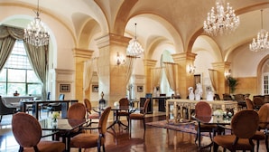 Um hall amplo com tetos altos, nichos em arco e elegantes lustres.