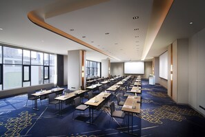 A conference room with rows of tables, chairs, and a large screen at the front. - Amari Bangkok (Bangkok)