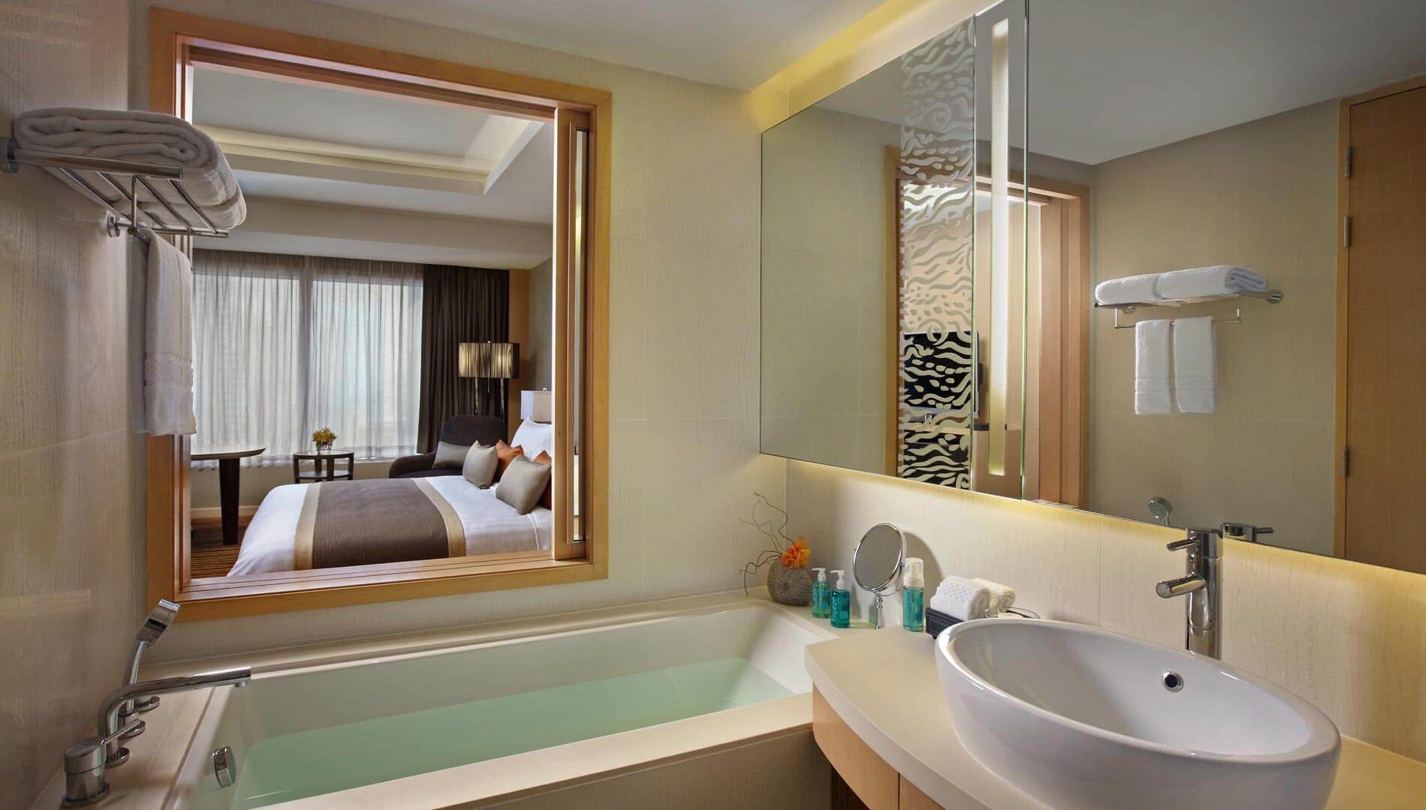A modern hotel bathroom with a large bathtub, a sink, and a mirror.