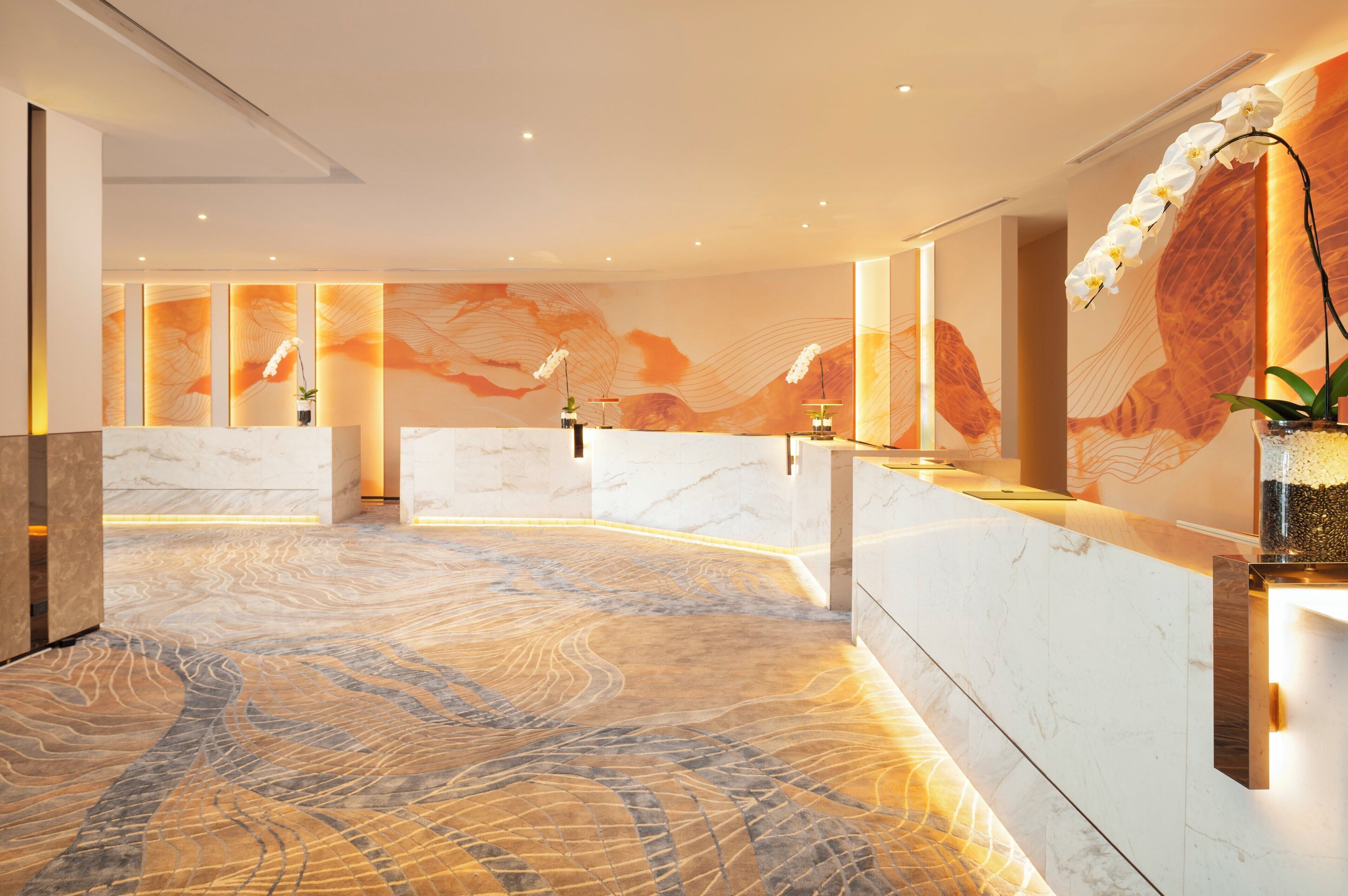 A modern reception area with marble counters, a patterned floor, and a large decorative wall.