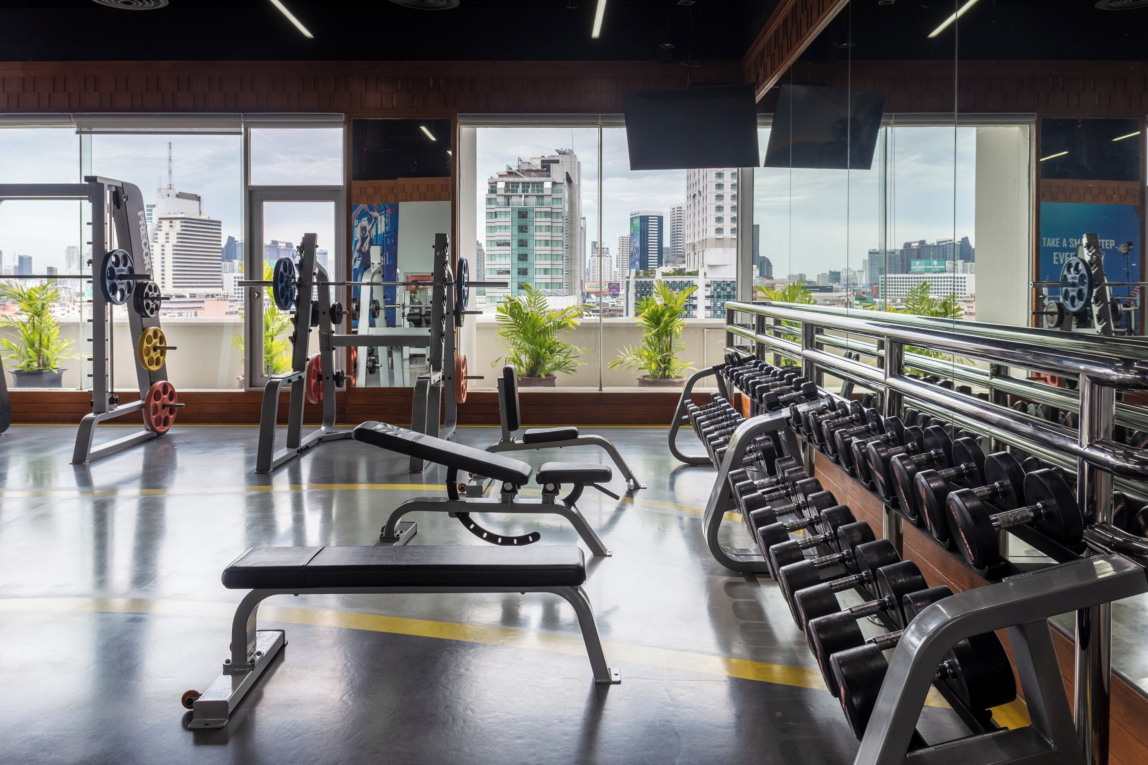 A gym with exercise equipment, large windows, and a city view.