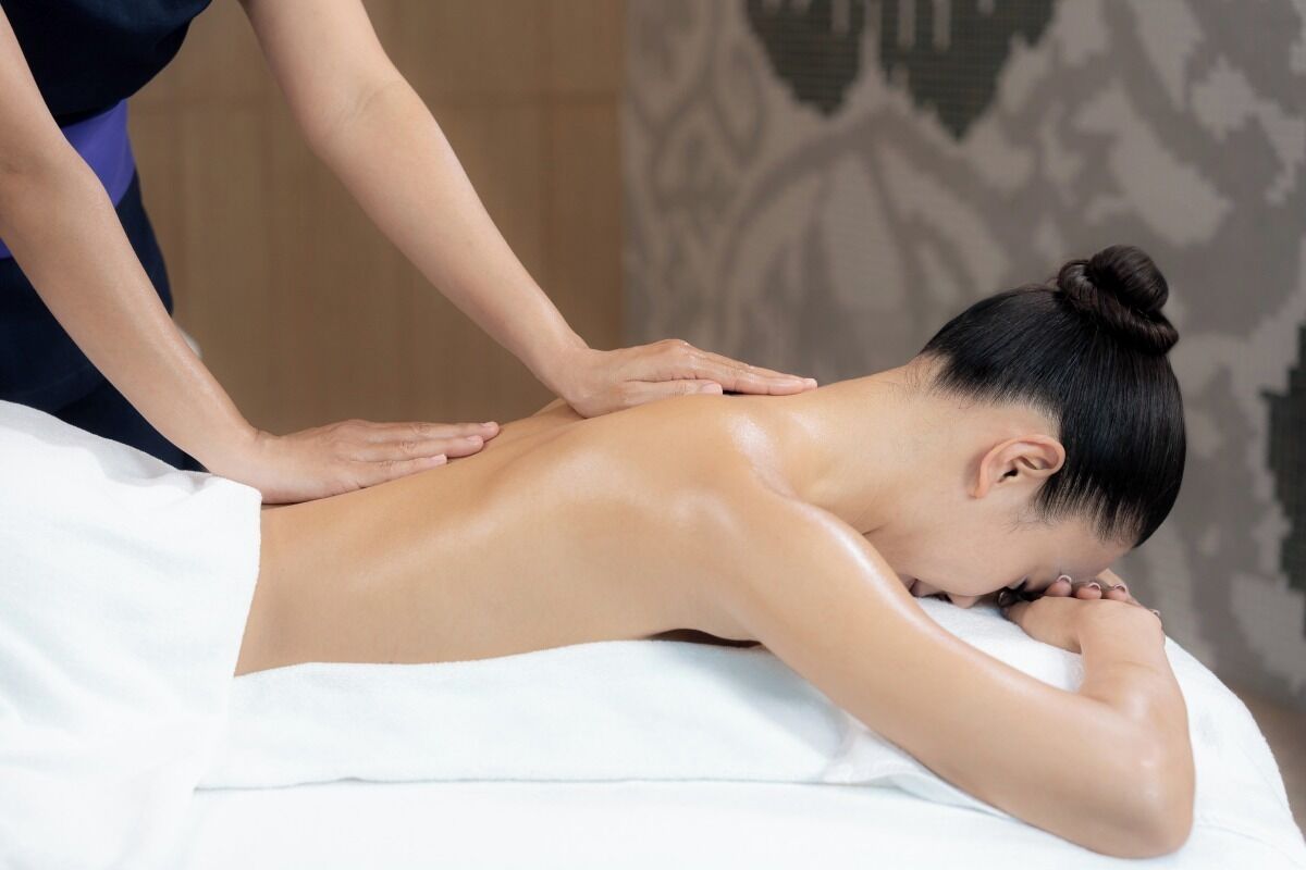 Eine Person bekommt eine Rückenmassage auf einer Massageliege.