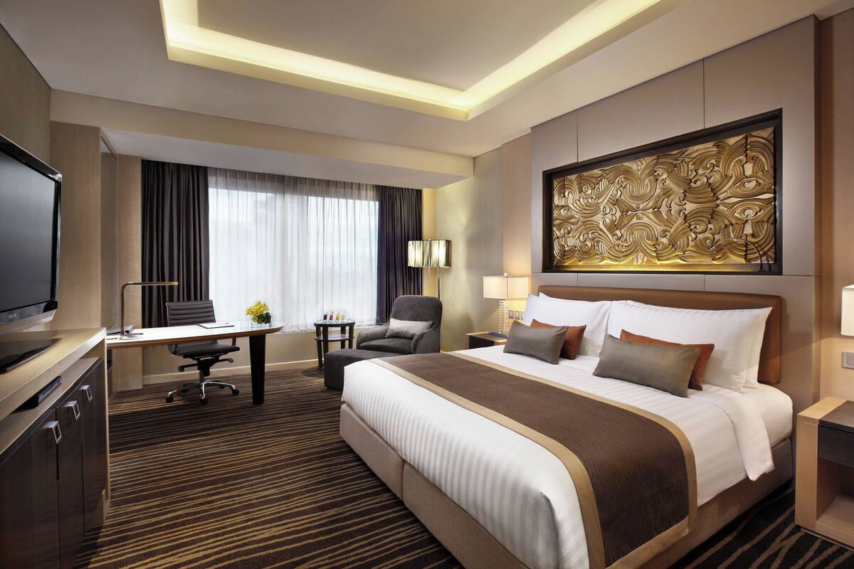 Une chambre d’hôtel avec un grand lit, un bureau, une chaise, une télévision et un élément décoratif mural.