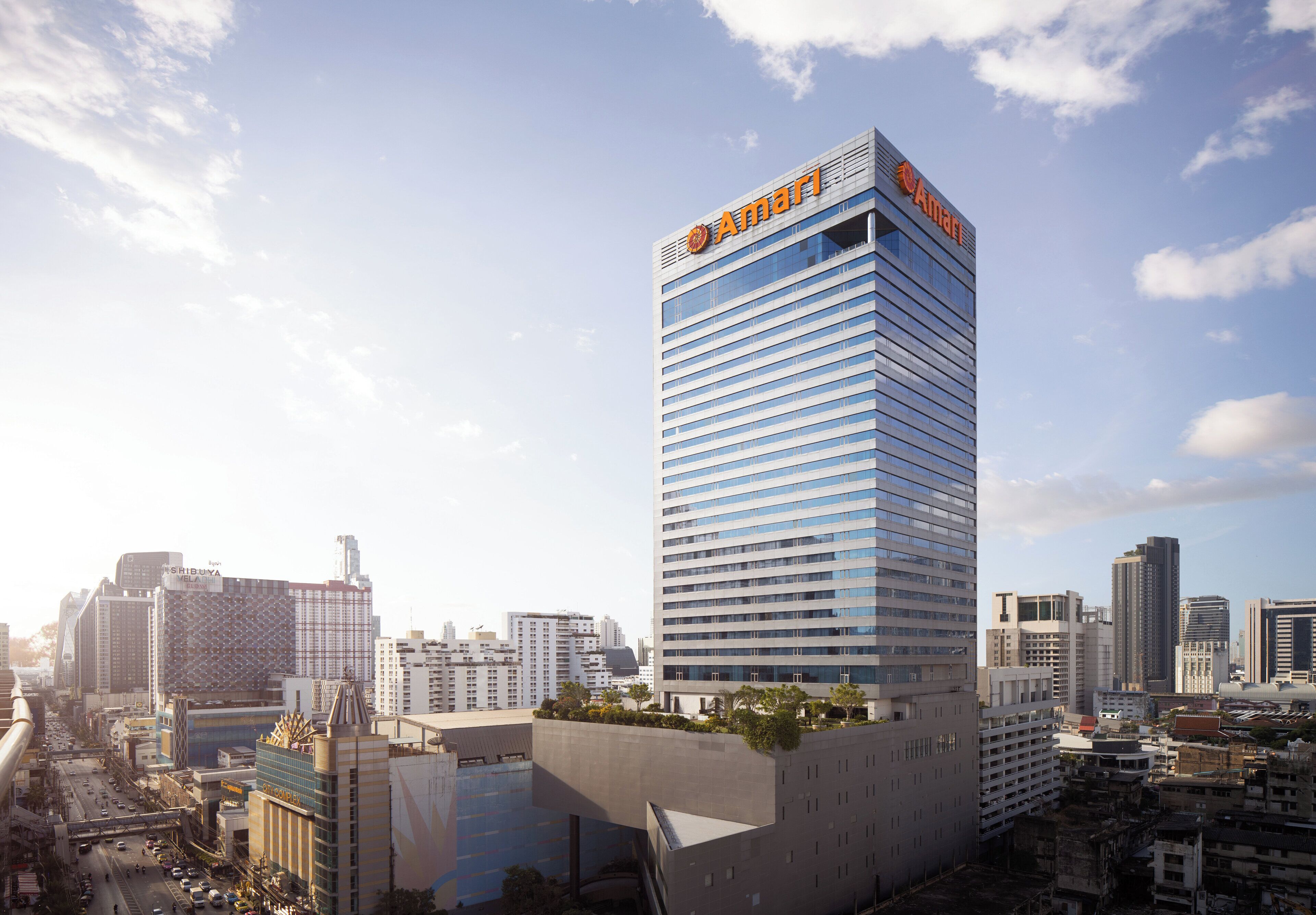A modern high-rise hotel with a prominent 'Amari' sign at the top, surrounded by other buildings in an urban setting.