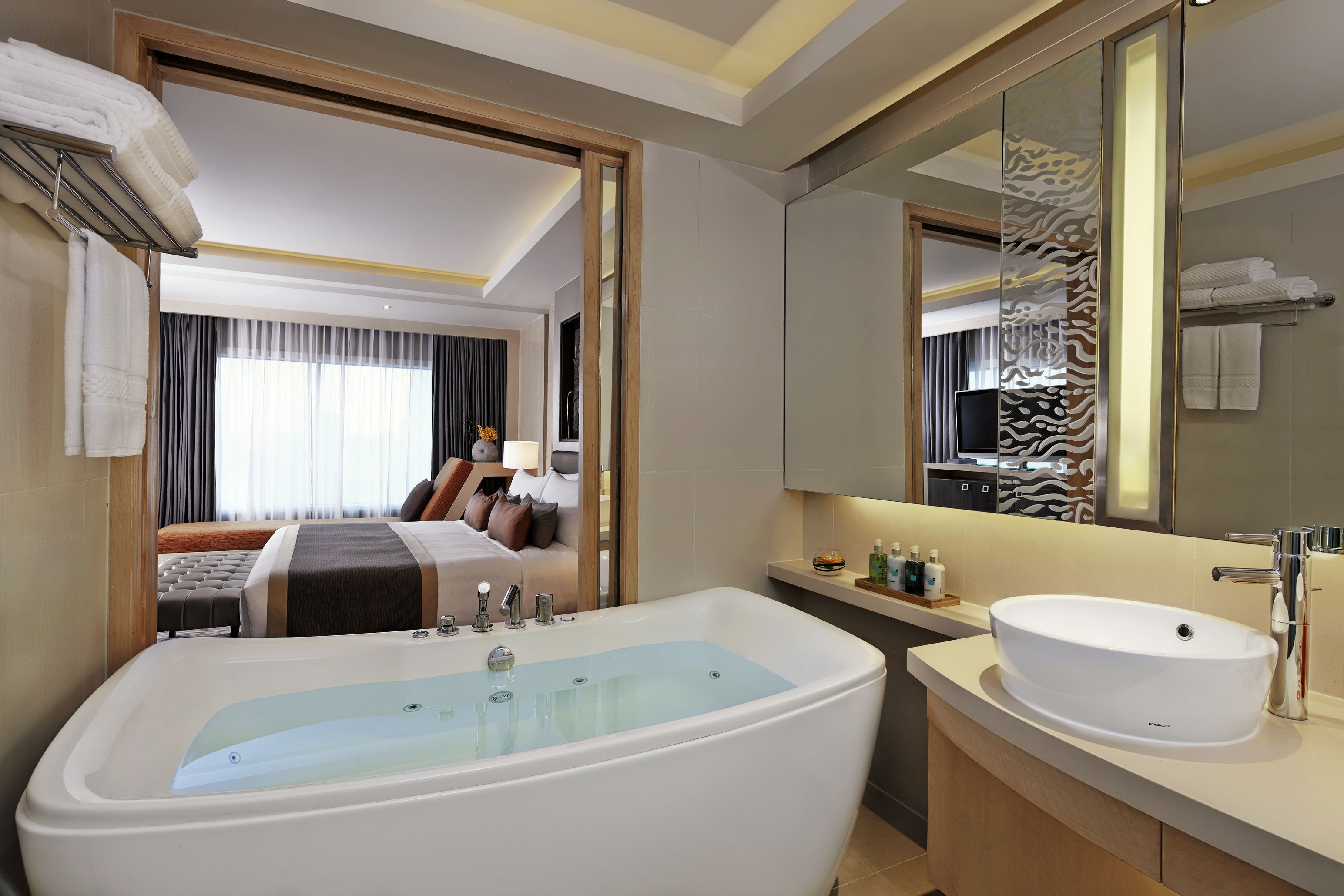Une salle de bain d’hôtel moderne, dotée d’une grande baignoire, d’un lavabo et d’un miroir.