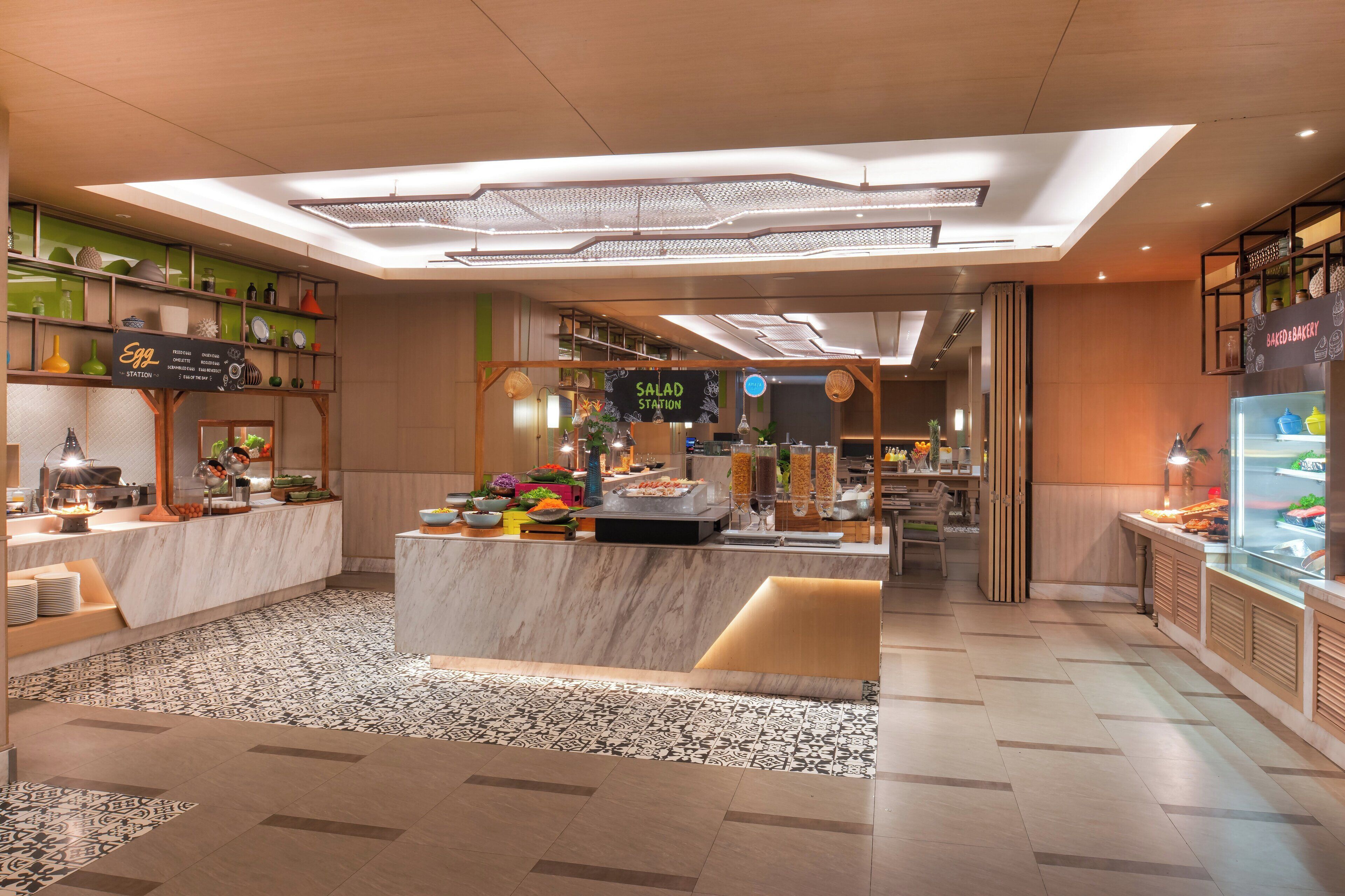 A modern hotel lobby with a central island, a reception desk, and a bakery counter.