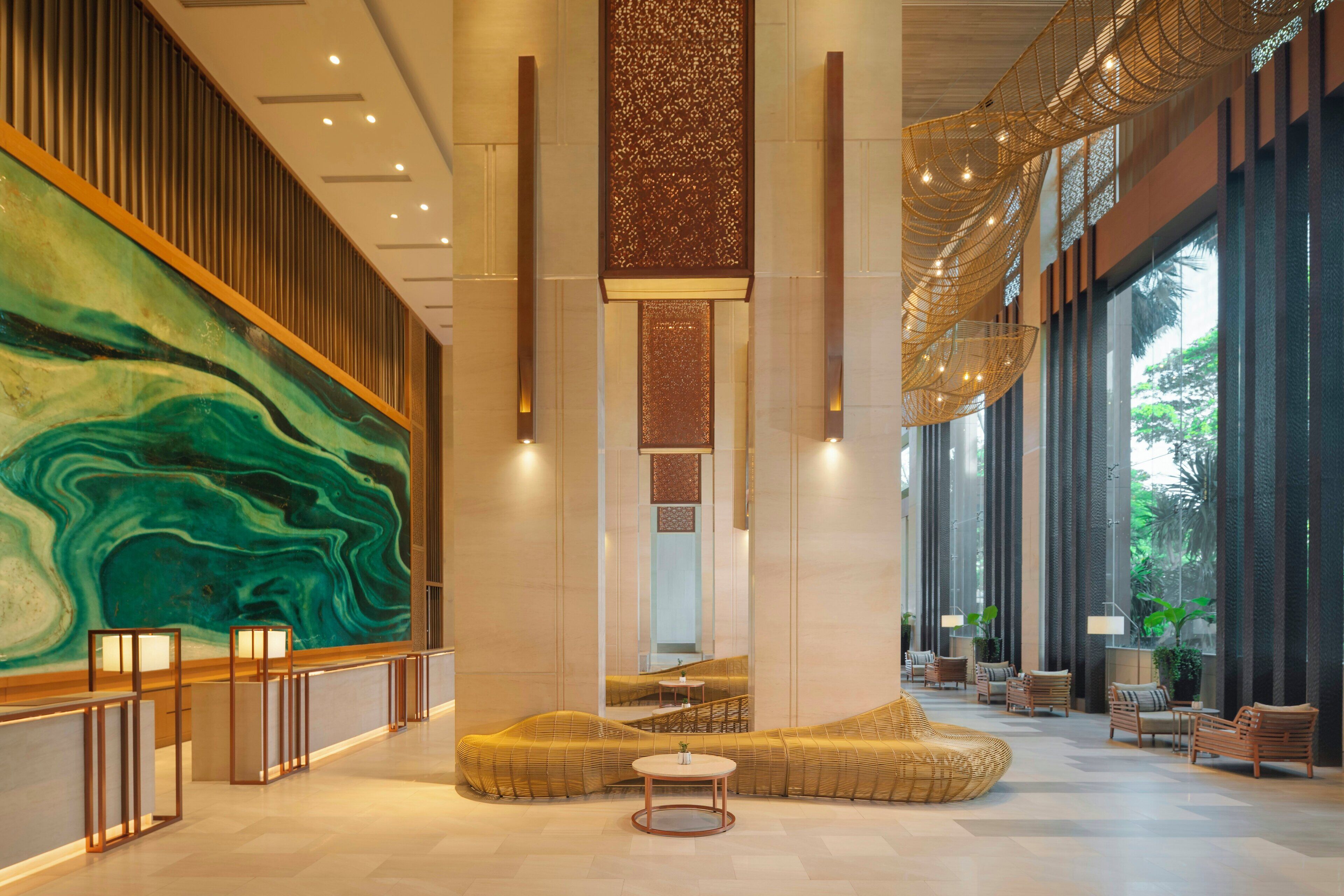 A spacious lobby with a large abstract mural, seating areas, and modern lighting fixtures.