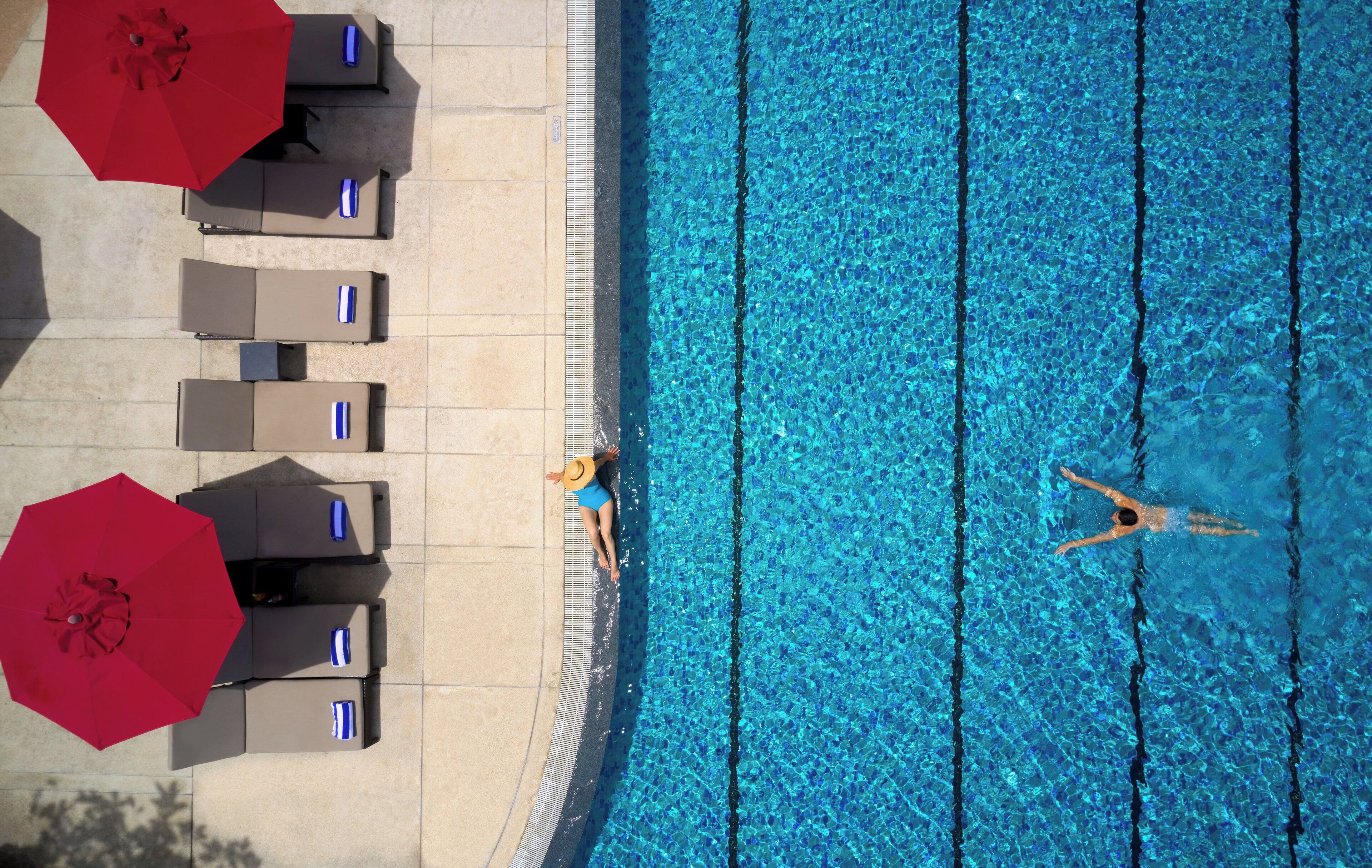 An aerial view of a swimming pool with lounge chairs and umbrellas.