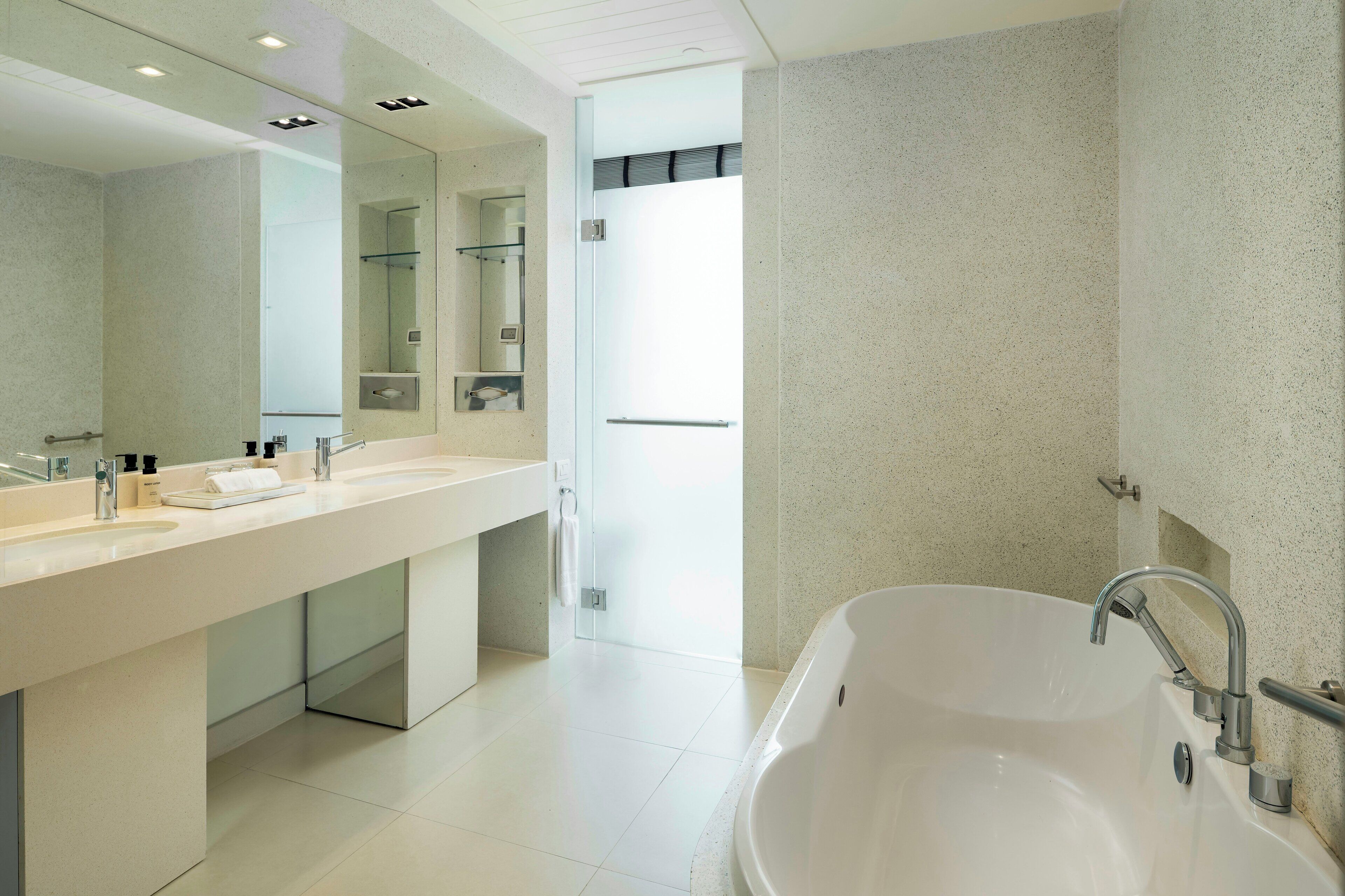 A modern bathroom with a large bathtub, a double sink vanity, and a glass shower enclosure.