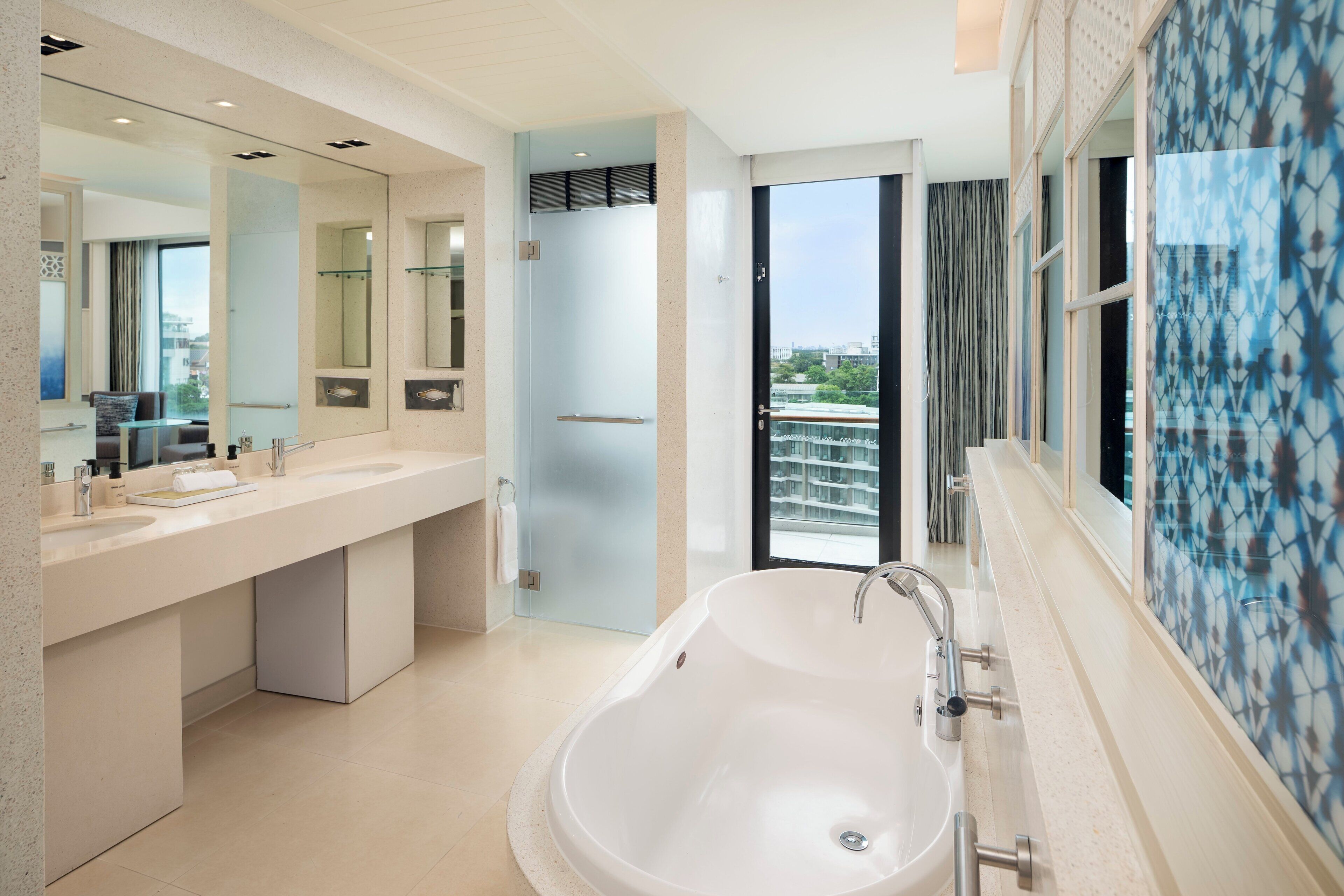 Une salle de bain moderne dotée d’une grande baignoire, de deux vasques et d’un grand miroir.