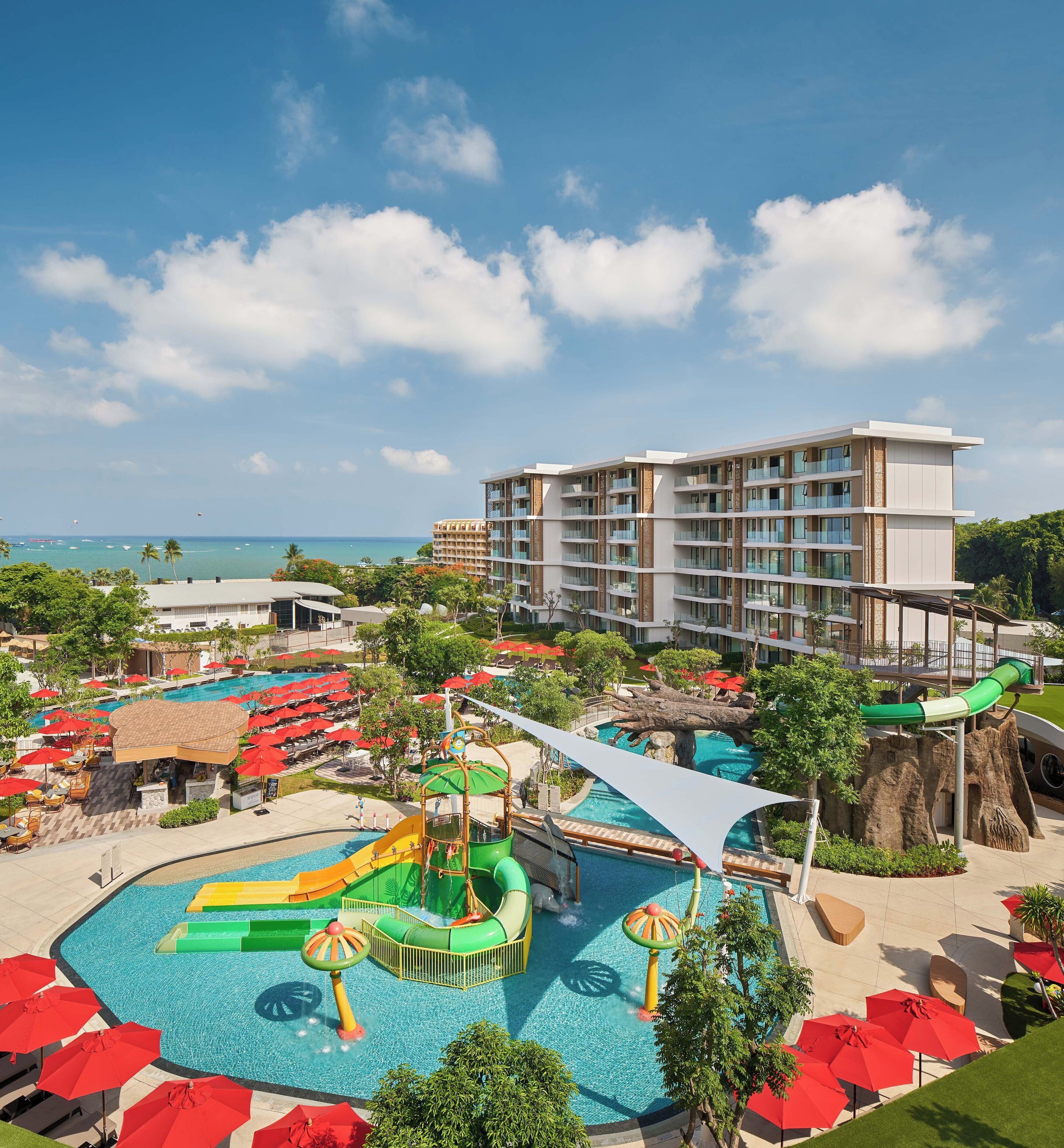 A resort with a swimming pool, water slides, and a view of the ocean.