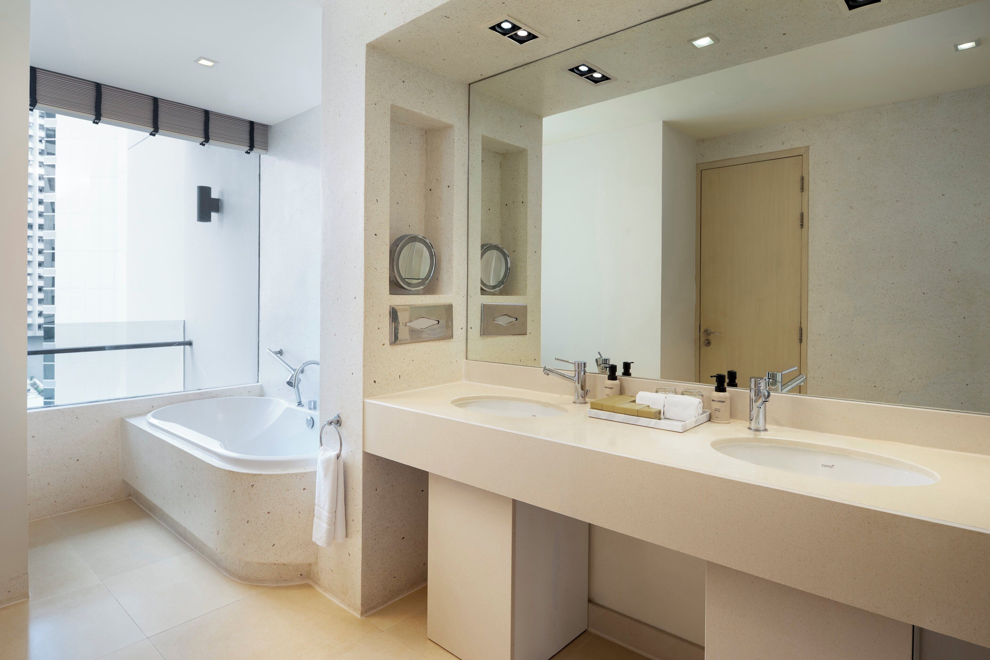 A modern bathroom with a freestanding bathtub, two sinks, and a large mirror.