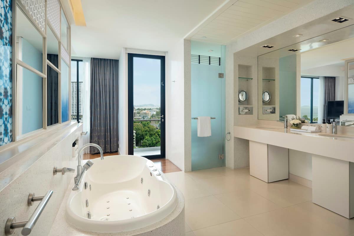 A modern bathroom with a large bathtub, a vanity with a mirror, and a view of a balcony.