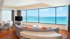A modern living room with a curved sofa, a flat-screen TV, and a view of the ocean. - Amari Pattaya (Pattaya)