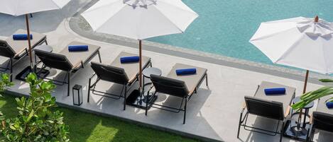 A poolside area with multiple white umbrellas, lounge chairs, and a clear view of the pool.