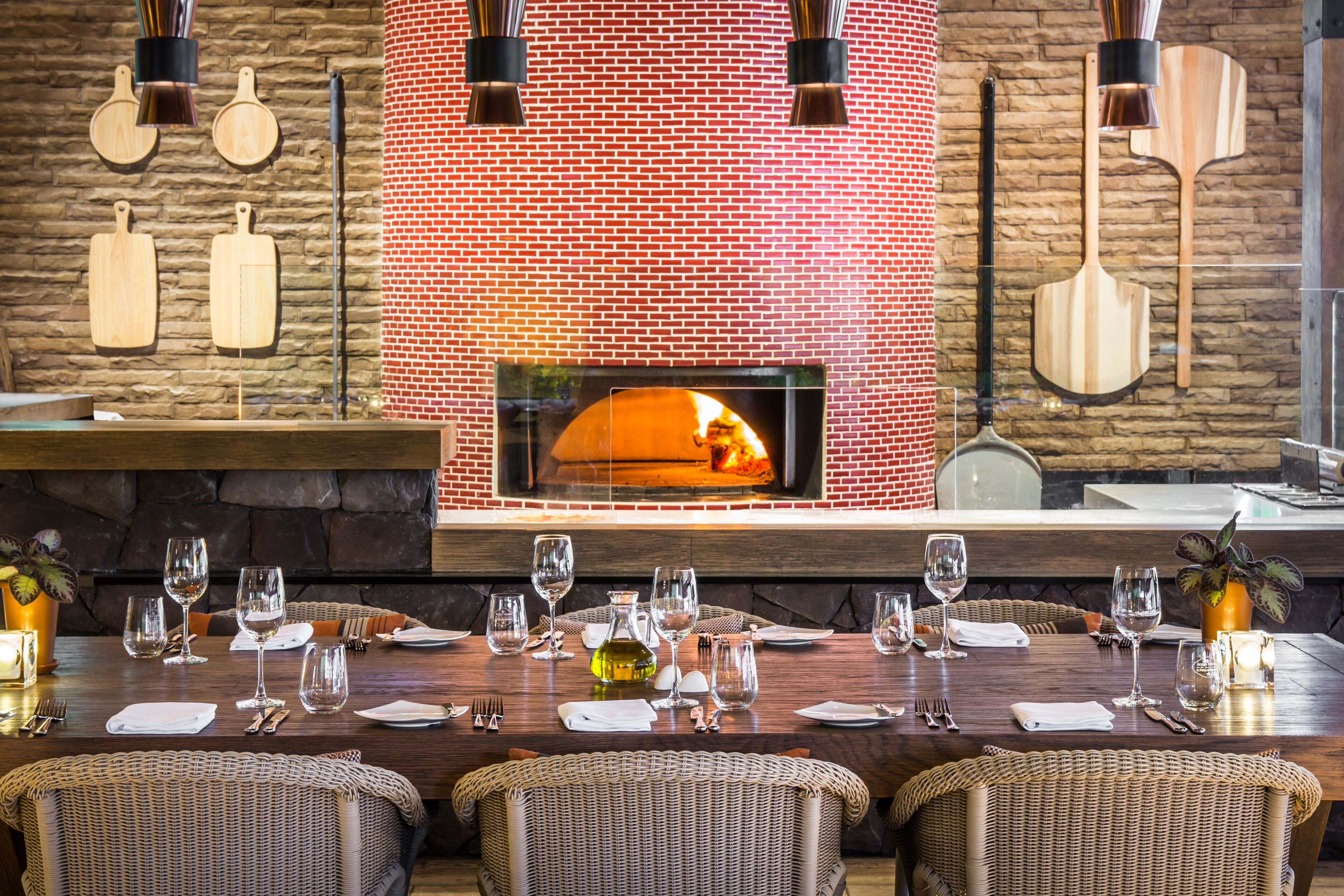 Un restaurante con pared de ladrillo, decoraciones de pala de madera para pizza y una chimenea.