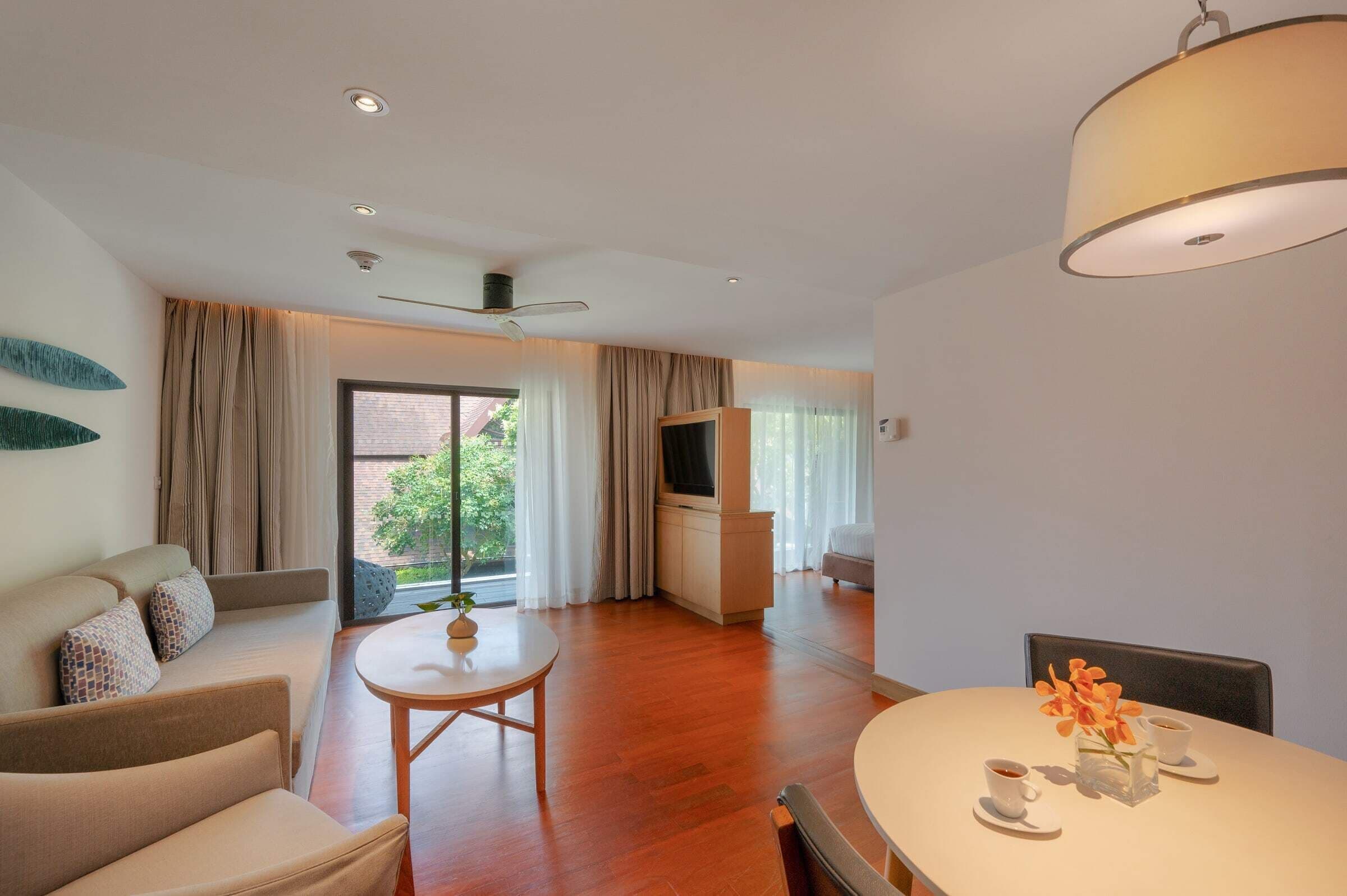 Una sala de estar moderna con un sofá, una mesa de centro y una mesa de comedor con un jarrón de flores.