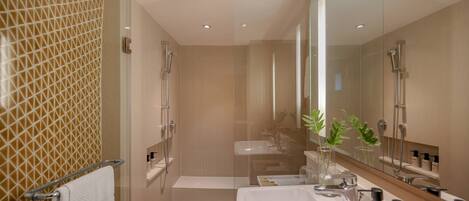 A modern bathroom with a glass-enclosed shower, a large mirror, and a vanity with a sink and countertop.