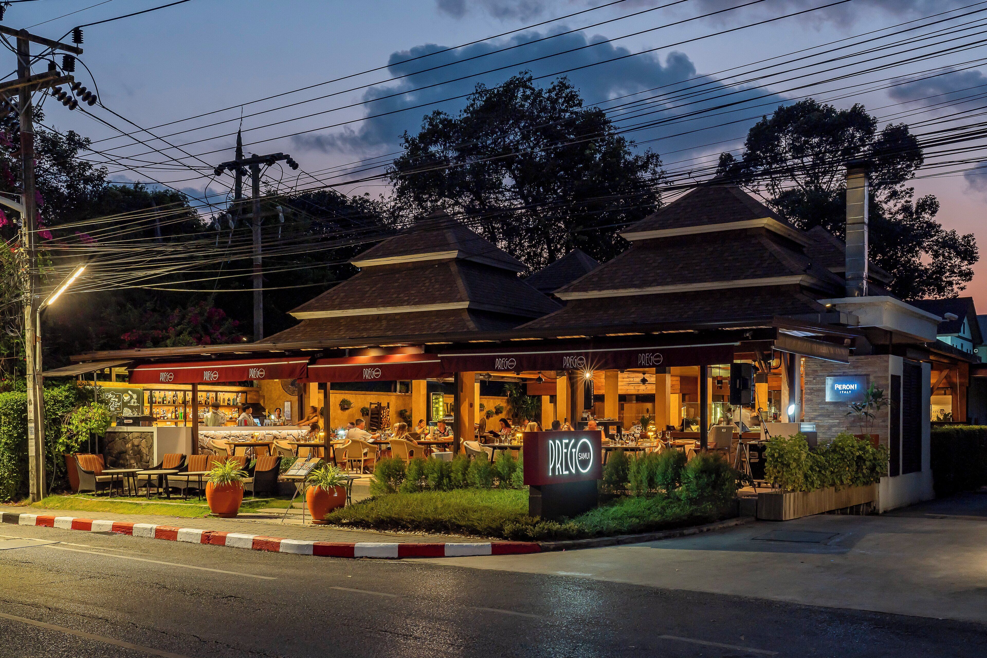Un restaurante con terraza, un letrero de neón y un estilo arquitectónico moderno.
