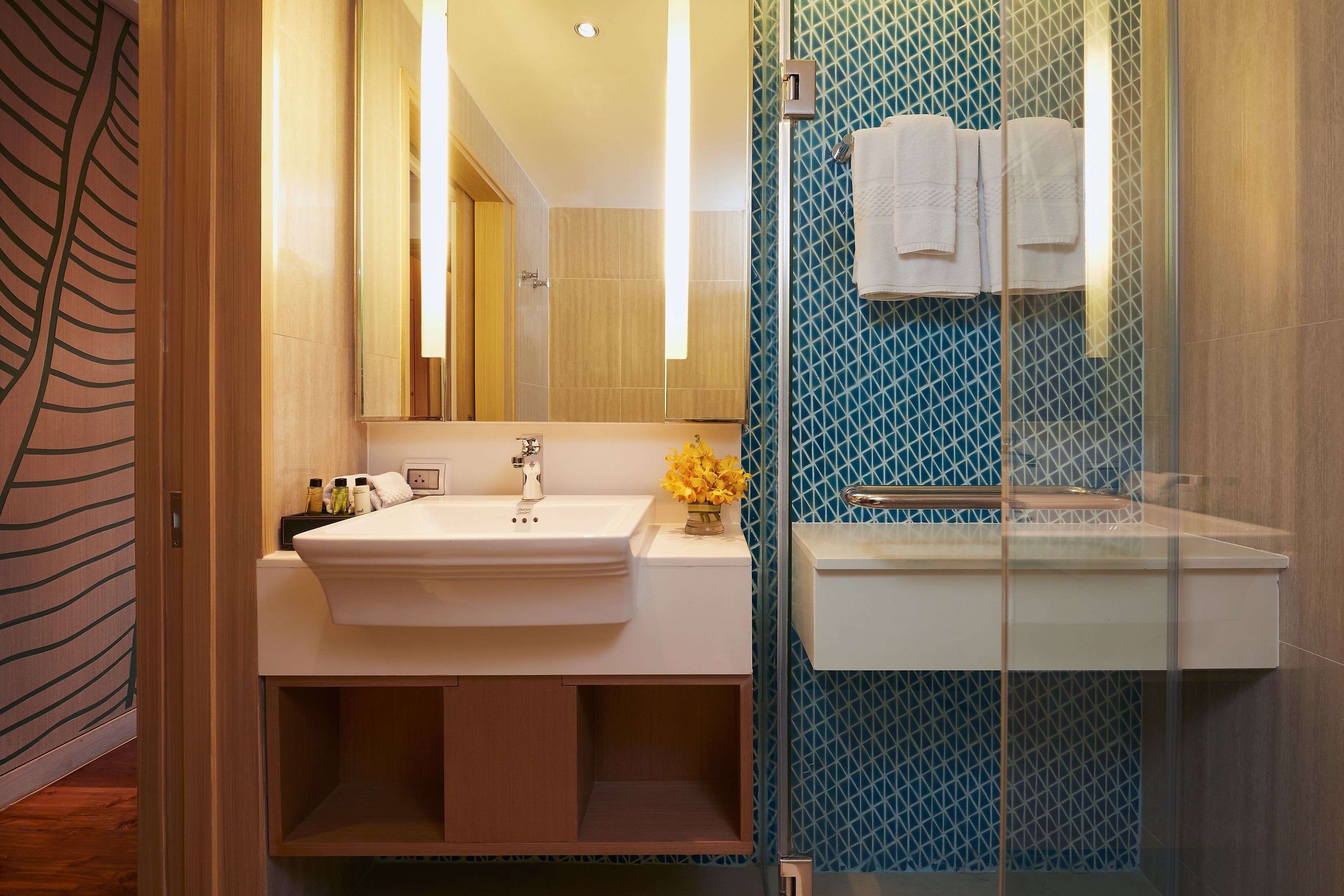 A modern bathroom with a large mirror, two sinks, and a shower area.