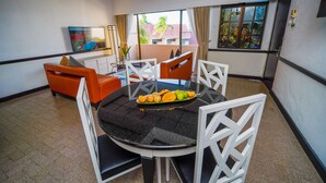A dining area with a round table, white chairs, and a fruit platter. - Holiday Villa Beach Resort & Spa Cherating (Cherating)