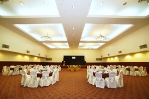 Conference room with tables, chairs, and chandeliers, ideal for presentations and events.