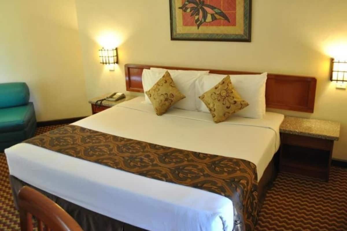 A hotel room with a bed, two bedside tables, a chair, and a wall-mounted artwork.