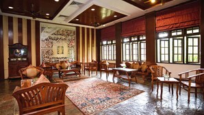 A spacious room with a large wooden table, several chairs, a decorative rug, and a traditional wall clock. - Holiday Villa Beach Resort & Spa Cherating (Cherating)