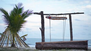 A wooden swing with a sign that reads "I ♥ HOLIDAY VILLA CHERATING" against a backdrop of palm trees and the ocean. - Holiday Villa Beach Resort & Spa Cherating (Cherating)