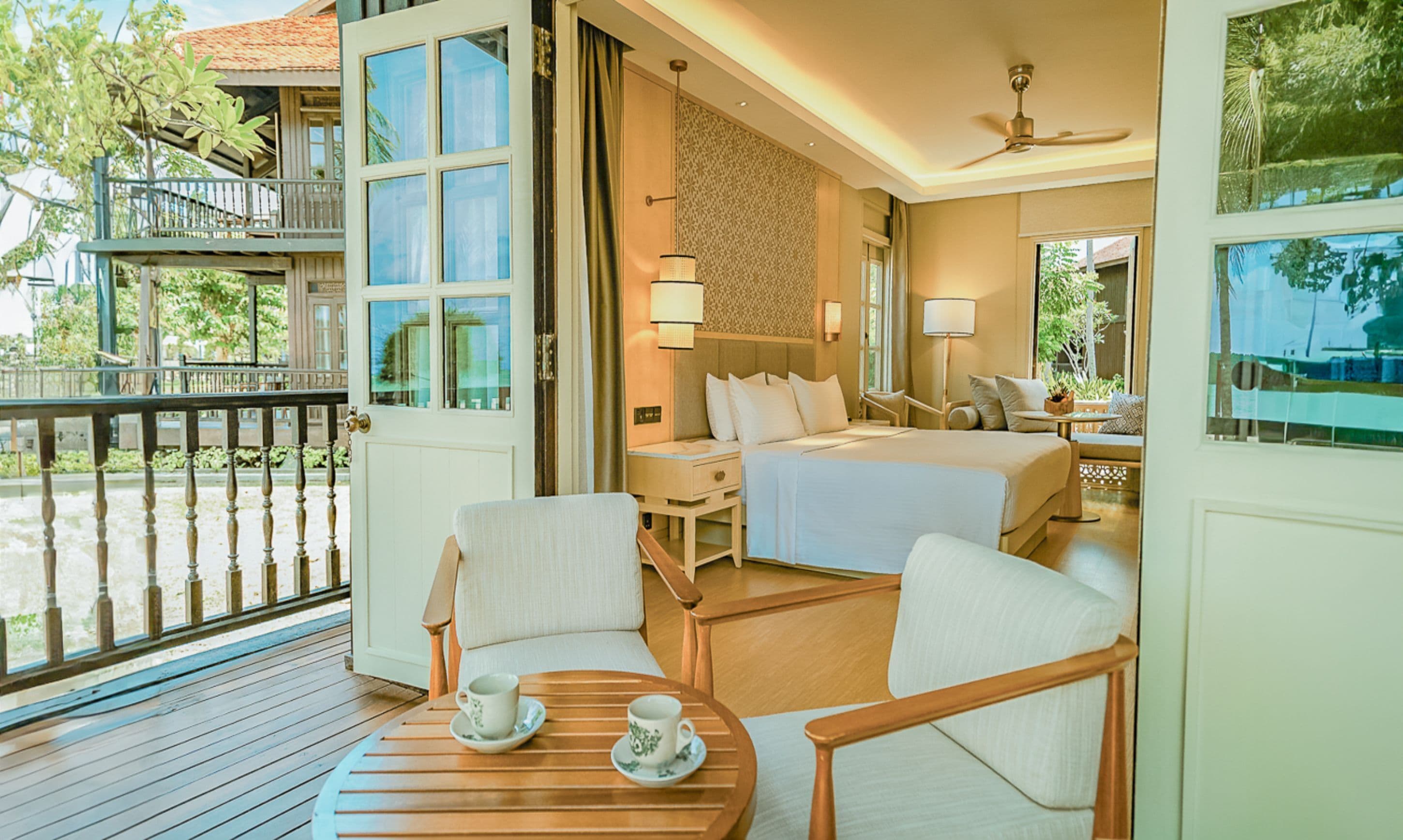 A hotel room with a balcony, a bed, a desk, and a chair.
