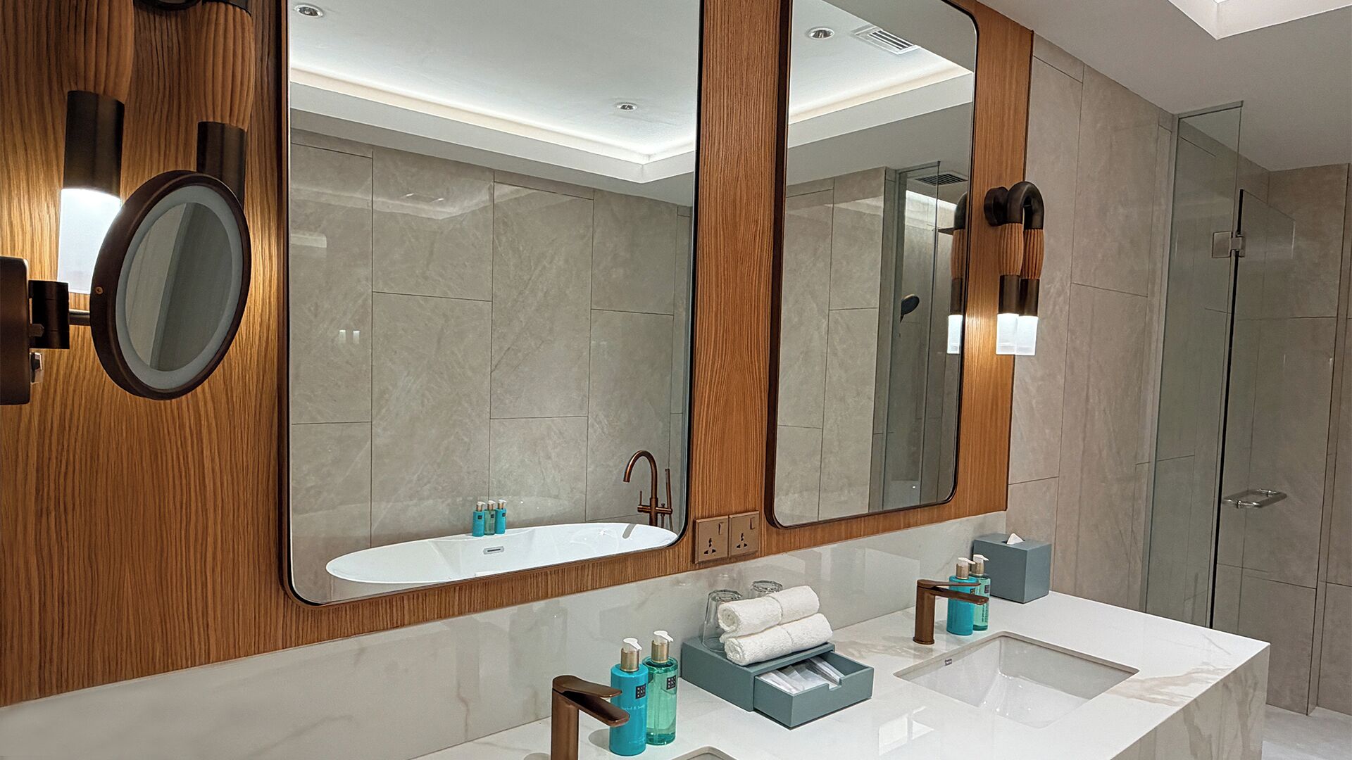 A modern bathroom with a large mirror, a sink, and a shower.