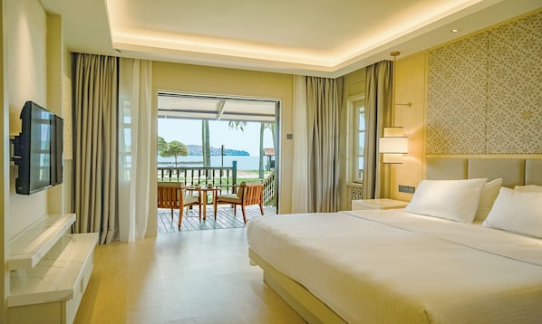A hotel room with a large bed, a TV, a balcony with a table and chairs, and a view of the sea. - Pelangi Beach Resort & Spa, Langkawi (Langkawi)