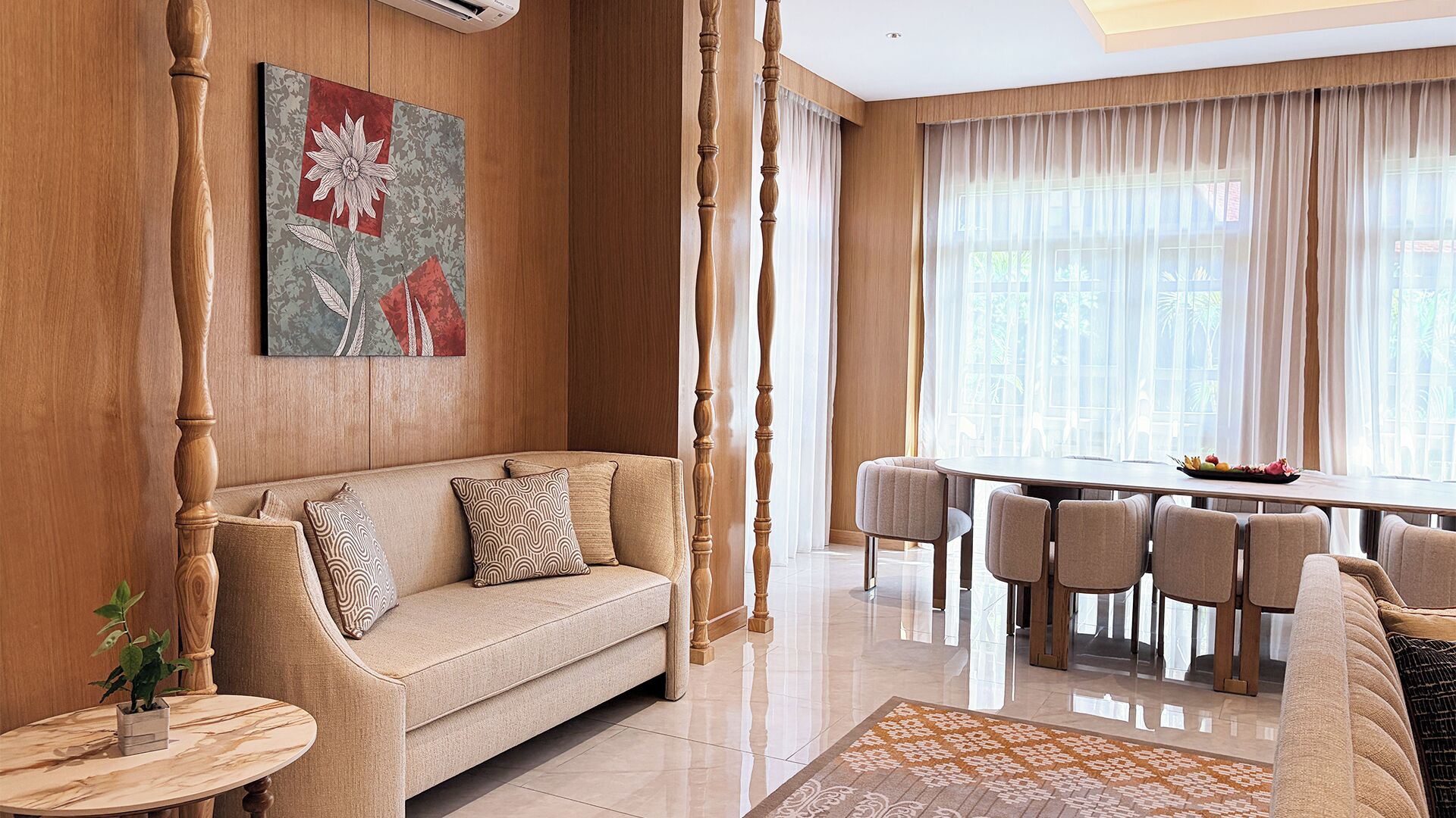 A living room with a sofa, a dining table with chairs, a coffee table, and a large window with curtains.