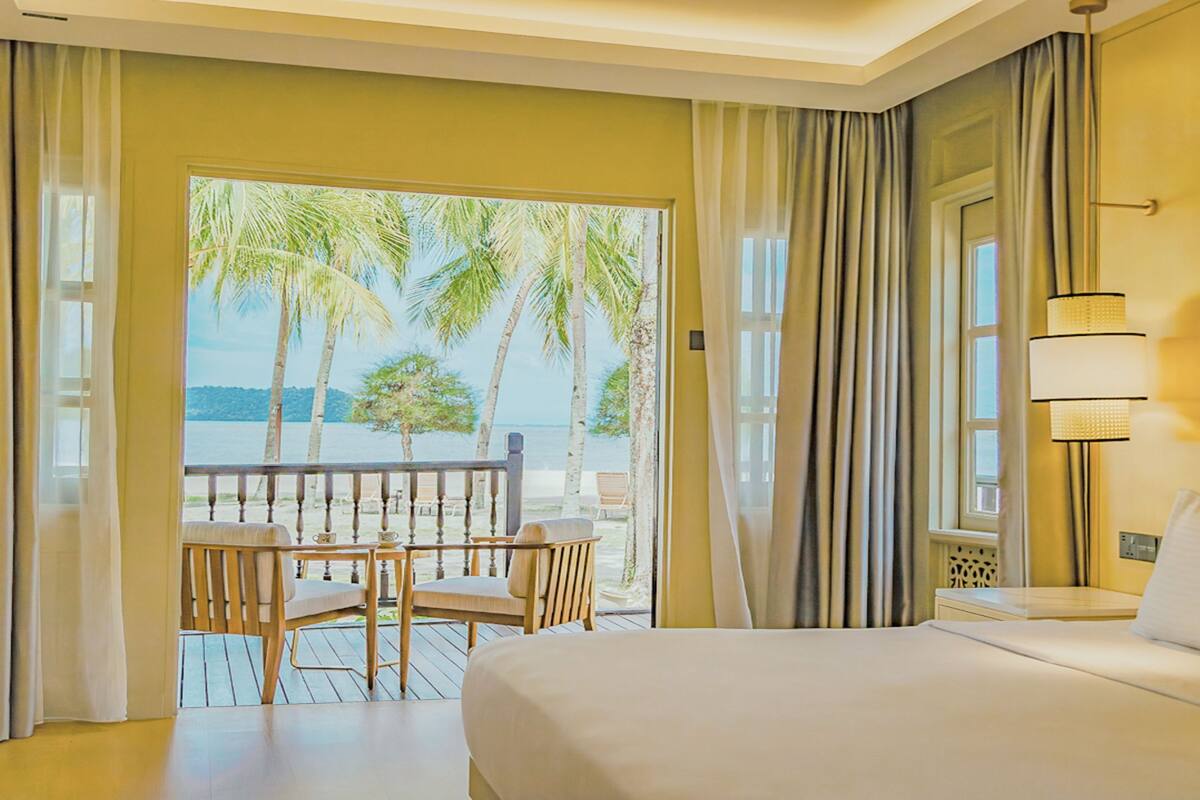 Quarto de hotel com varanda, cama, mesa e cadeiras.