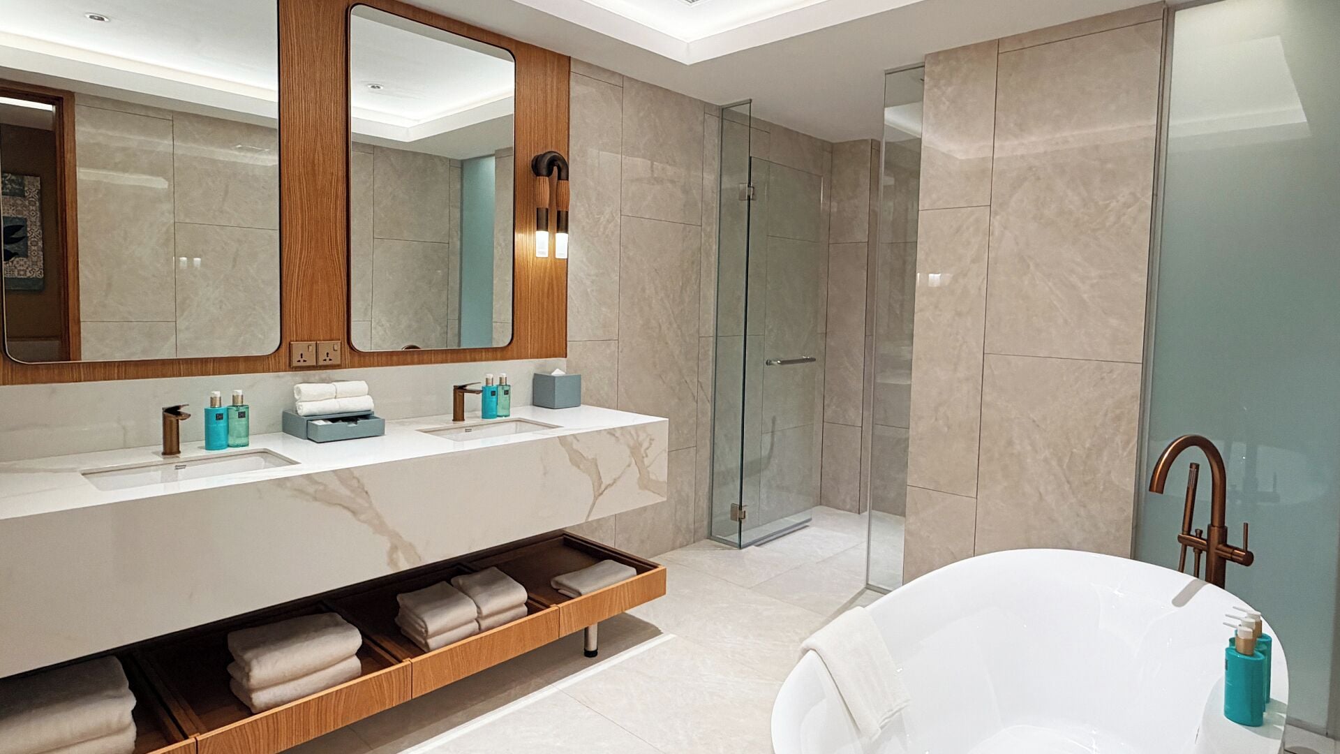 Un baño moderno con un espejo grande, cabina de ducha de vidrio, tocador con lavabo y bañera.