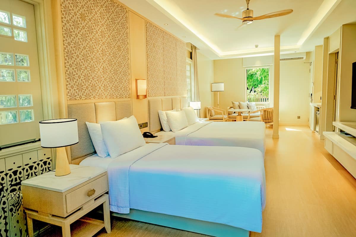 Quarto de hotel com duas camas, televisão, escrivaninha e uma cadeira.